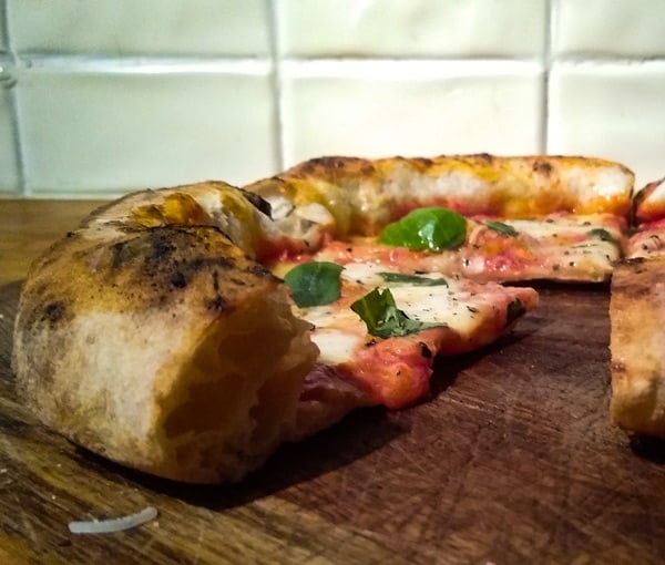 Neapolitan pizza slice up close on wooden board