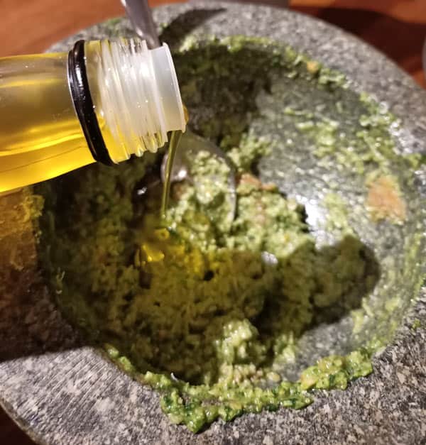 Adding olive oil to pesto for pizza